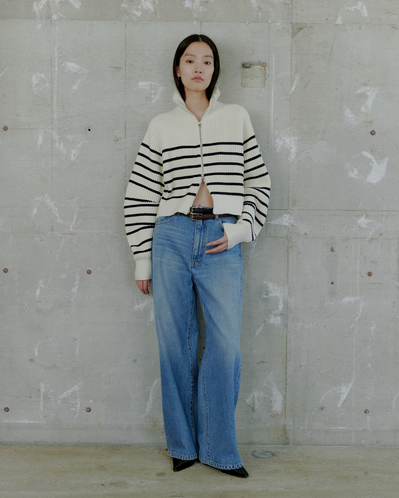 ハイネックニットジップアップカーディガン&サイドラインエフェクトデニムを着用した女性