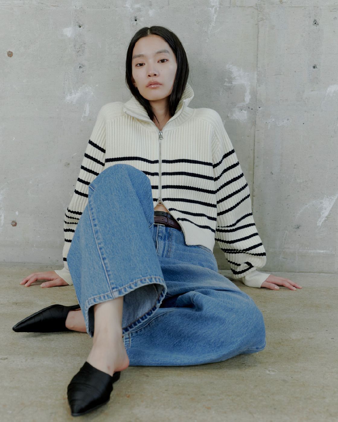 ハイネックニットジップアップカーディガン&サイドラインエフェクトデニムを着用した女性