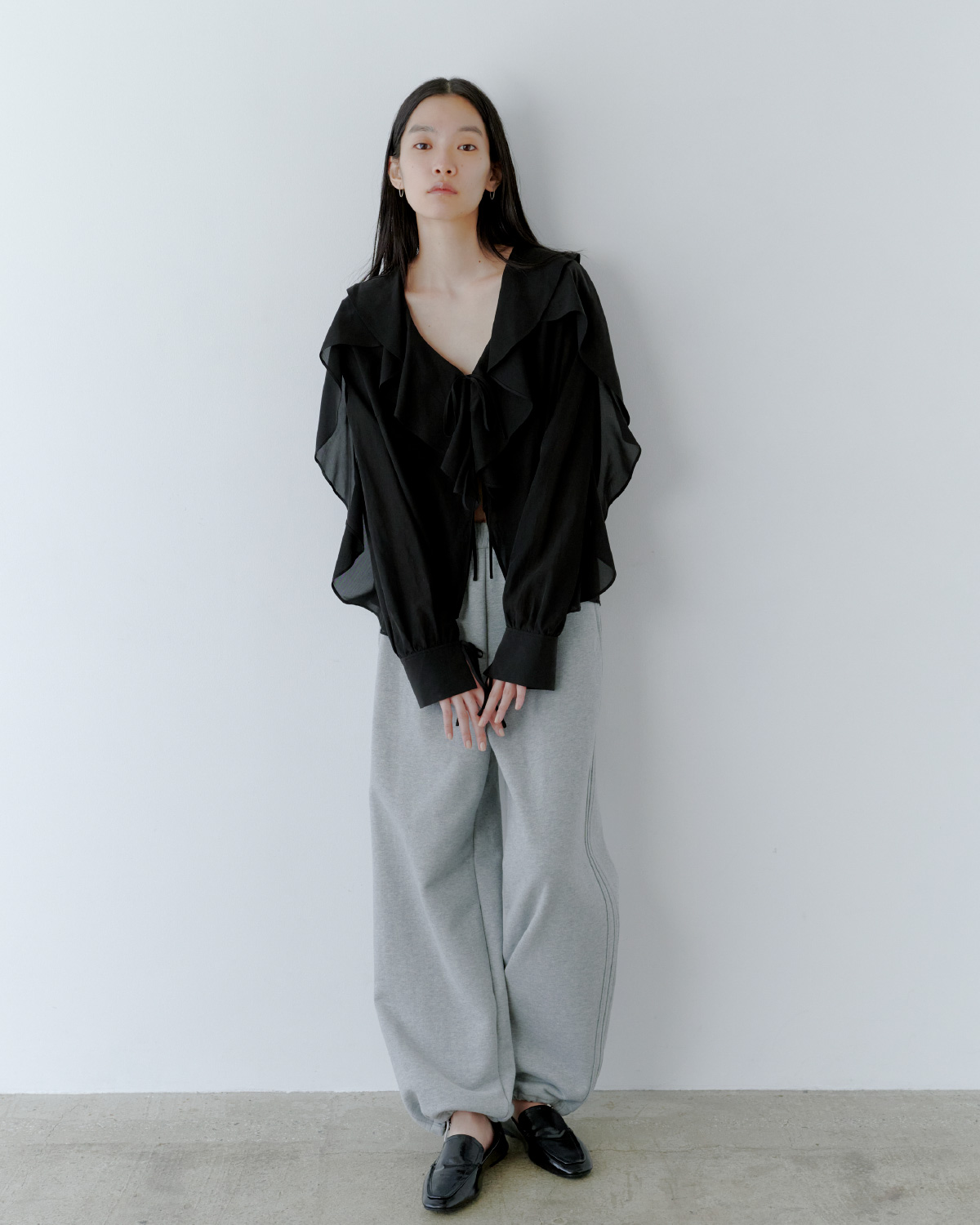 フードマフラー付きスプリングコート&スウェット短丈ジップトップス&サイドラインスウェットパンツを着用した女性